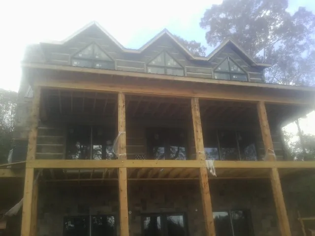 Dormers and porch framing on a large log home under construction — Roof Coating work by our crew in Panama
