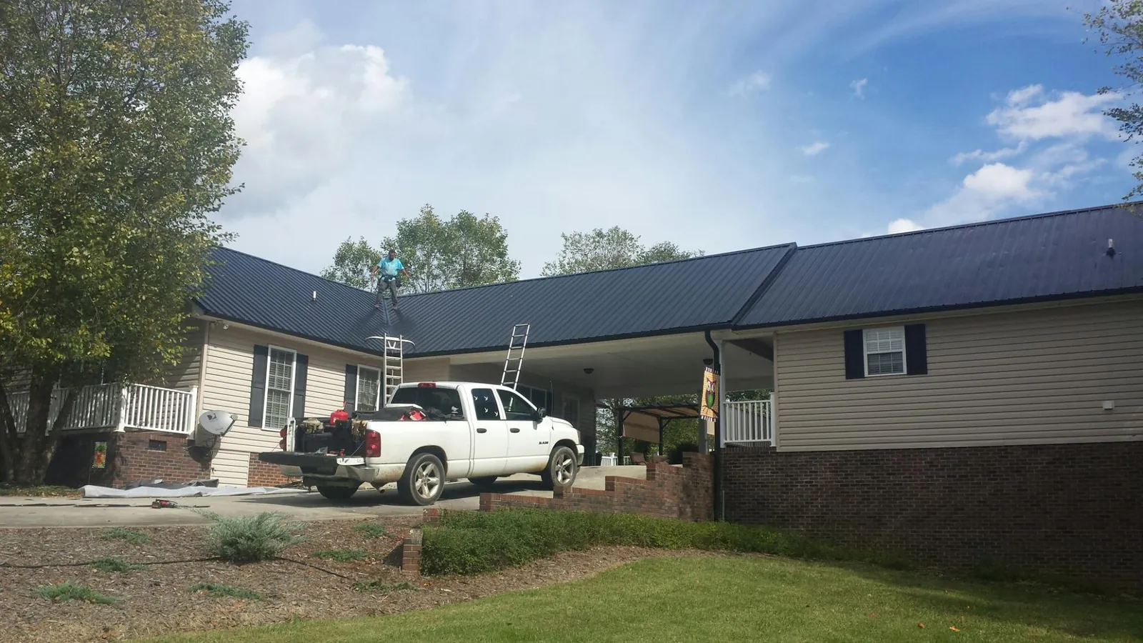 Black metal roof over a home and attached breezeway with ladders set in Panama